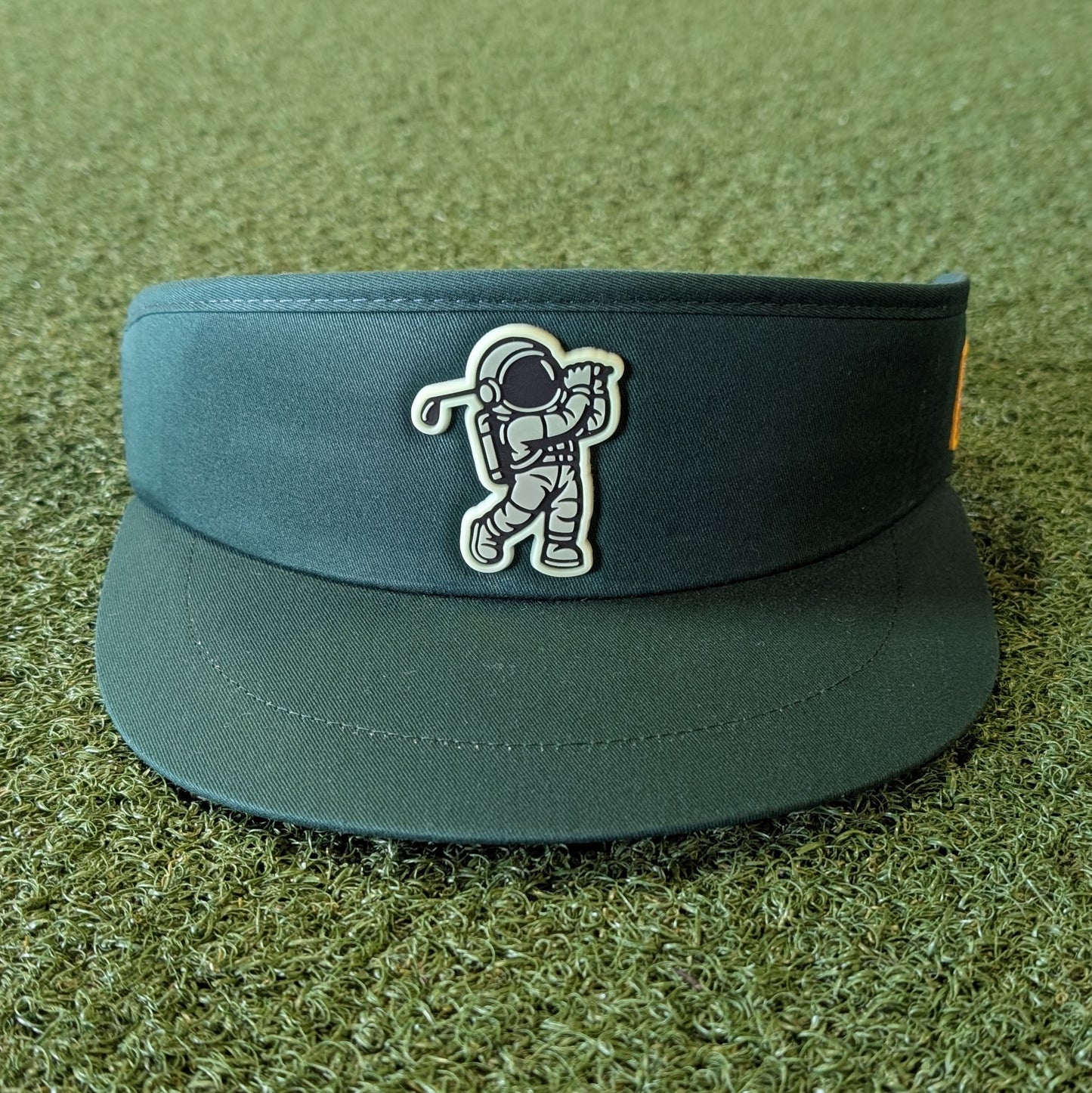 Green golf visor with astronaut design on a grassy background