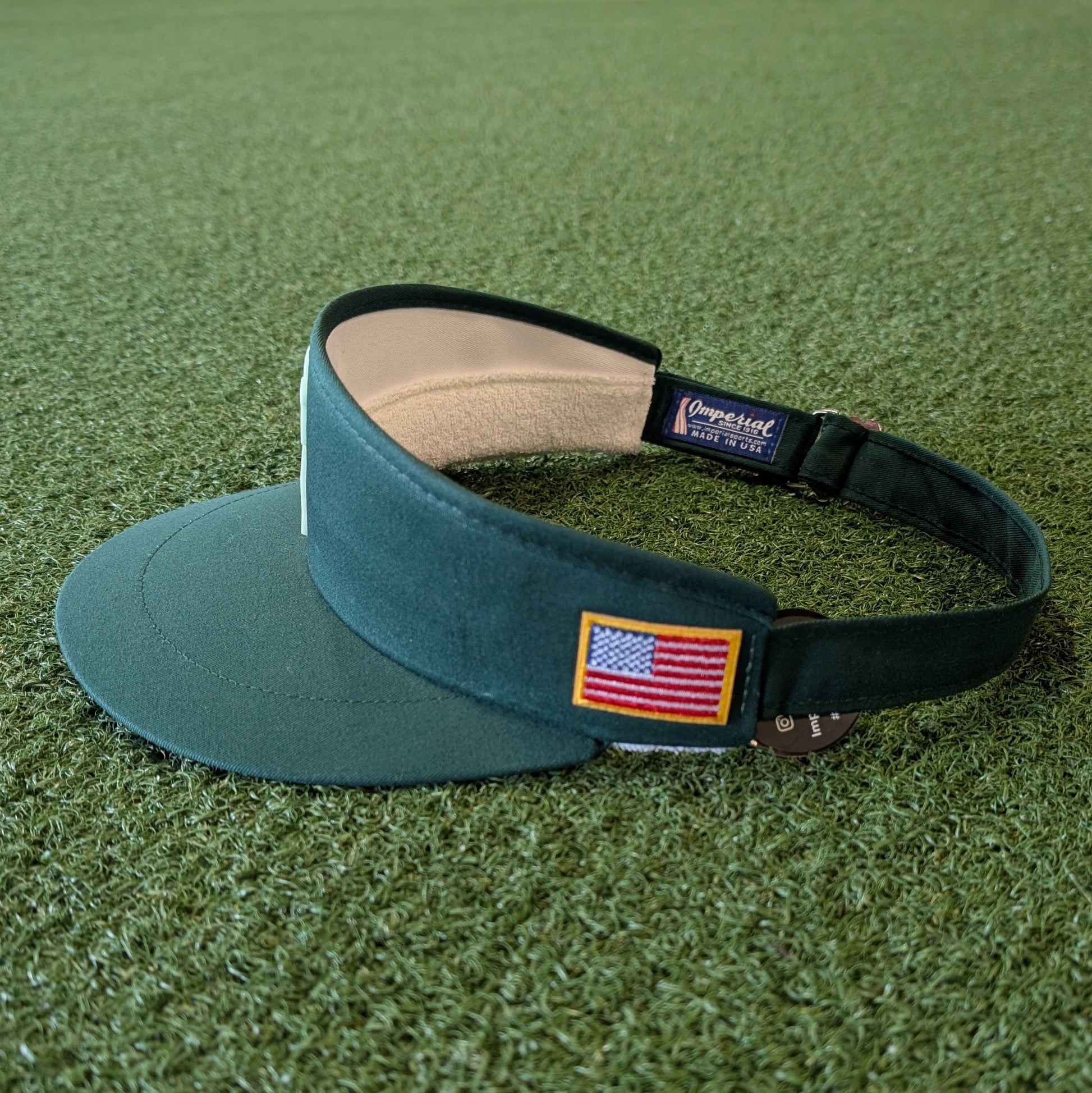 Green golf visor with American flag patch on a green grass background